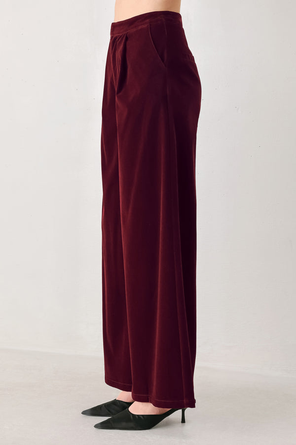 A person wearing high-waisted, wide-leg burgundy velvet pants with black pointed-toe heels | FREEMARKET