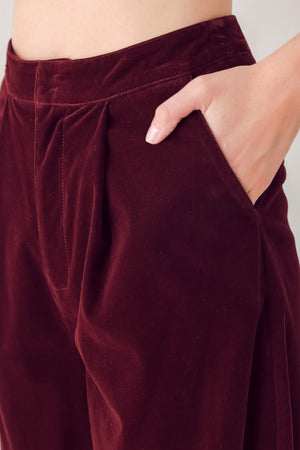 A person wearing high-waisted, wide-leg burgundy velvet pants with black pointed-toe heels | FREEMARKET