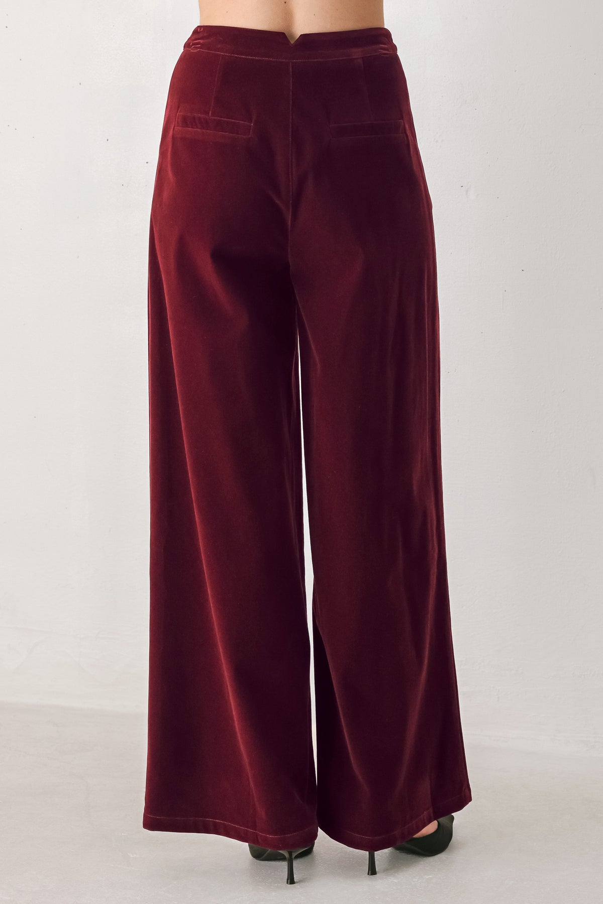 A person wearing high-waisted, wide-leg burgundy velvet pants with black pointed-toe heels | FREEMARKET