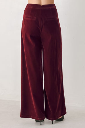 A person wearing high-waisted, wide-leg burgundy velvet pants with black pointed-toe heels | FREEMARKET
