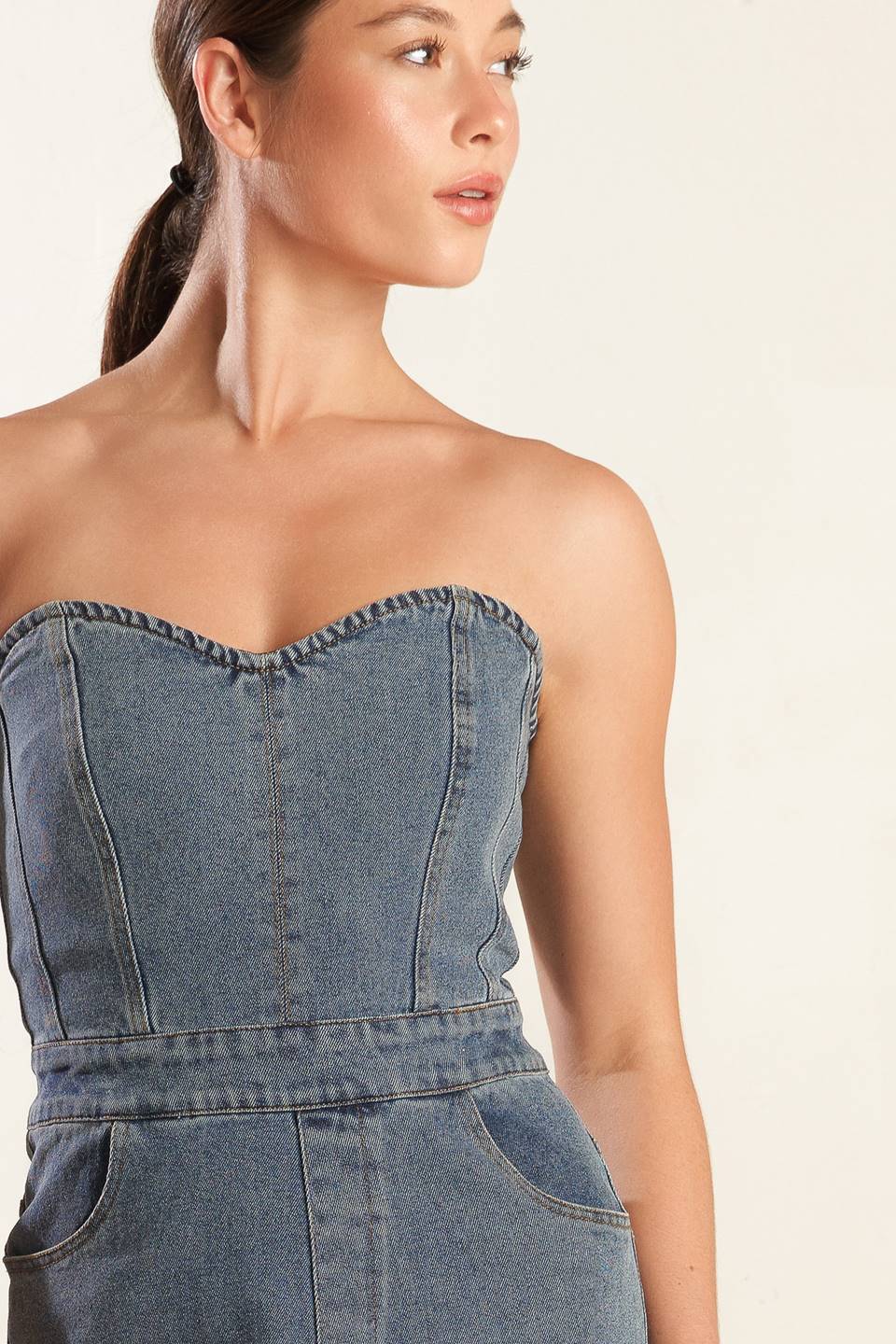 A strapless, washed blue denim jumpsuit featuring sweetheart neckline, side pockets, wide leg and back zipper closure.