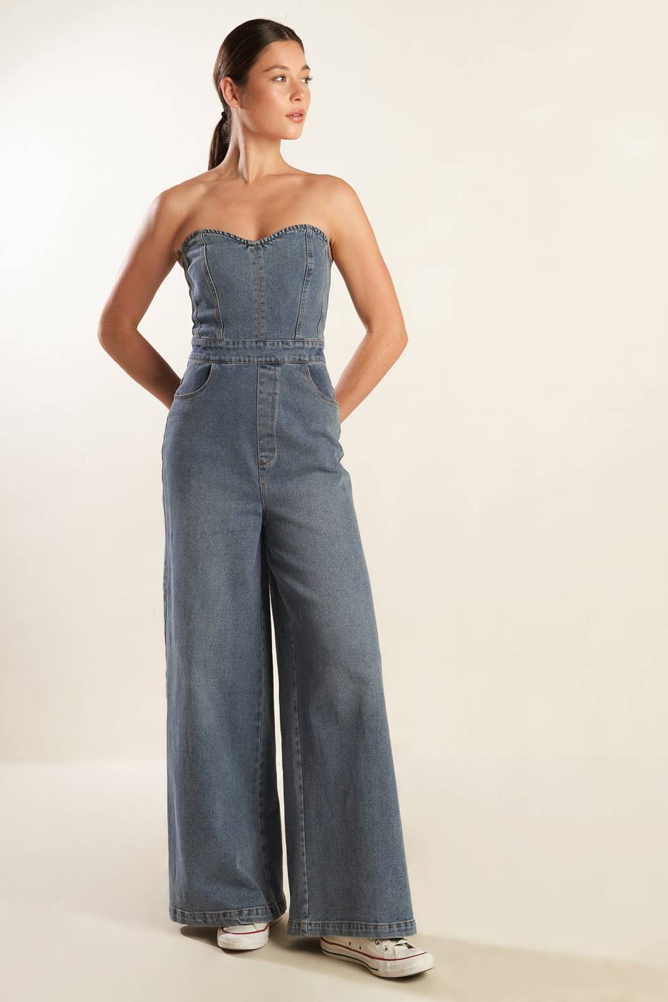 A strapless, washed blue denim jumpsuit featuring sweetheart neckline, side pockets, wide leg and back zipper closure.