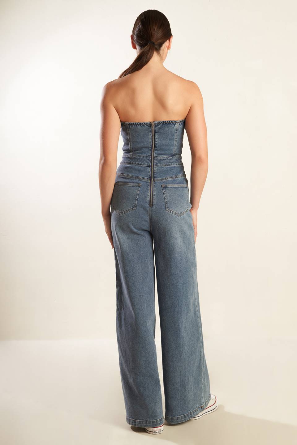 A strapless, washed blue denim jumpsuit featuring sweetheart neckline, side pockets, wide leg and back zipper closure.