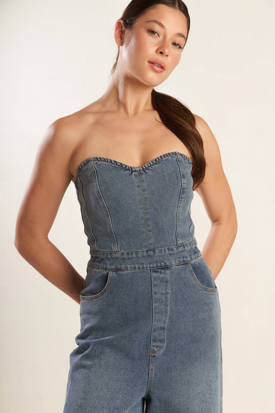 A strapless, washed blue denim jumpsuit featuring sweetheart neckline, side pockets, wide leg and back zipper closure.