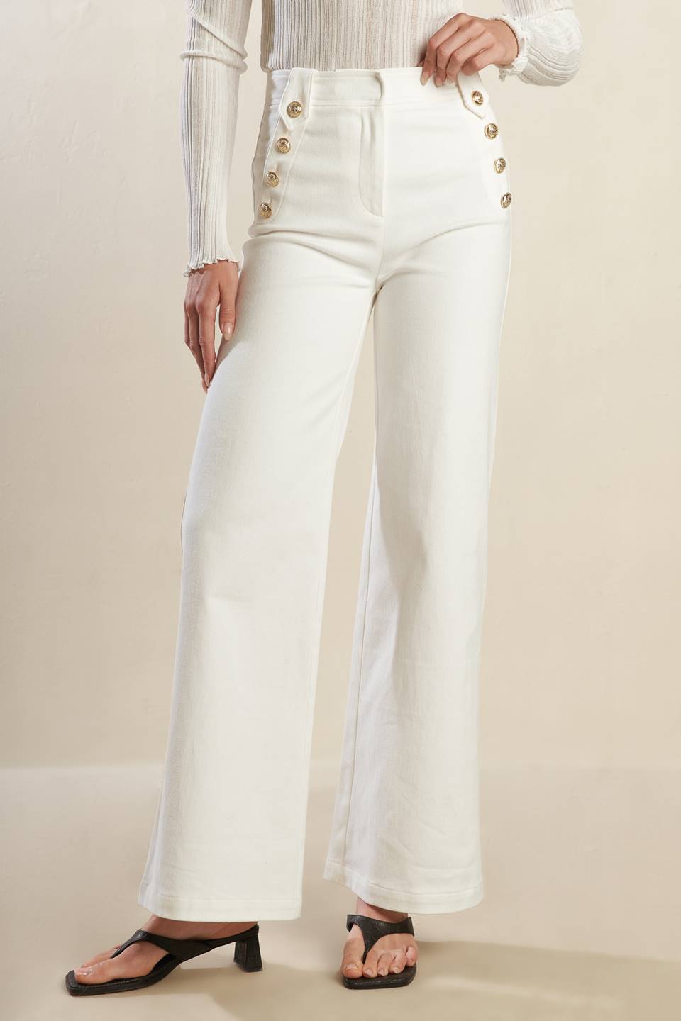 A solid woven white pant featuring front closure, button detail at pocket opening and wide leg.