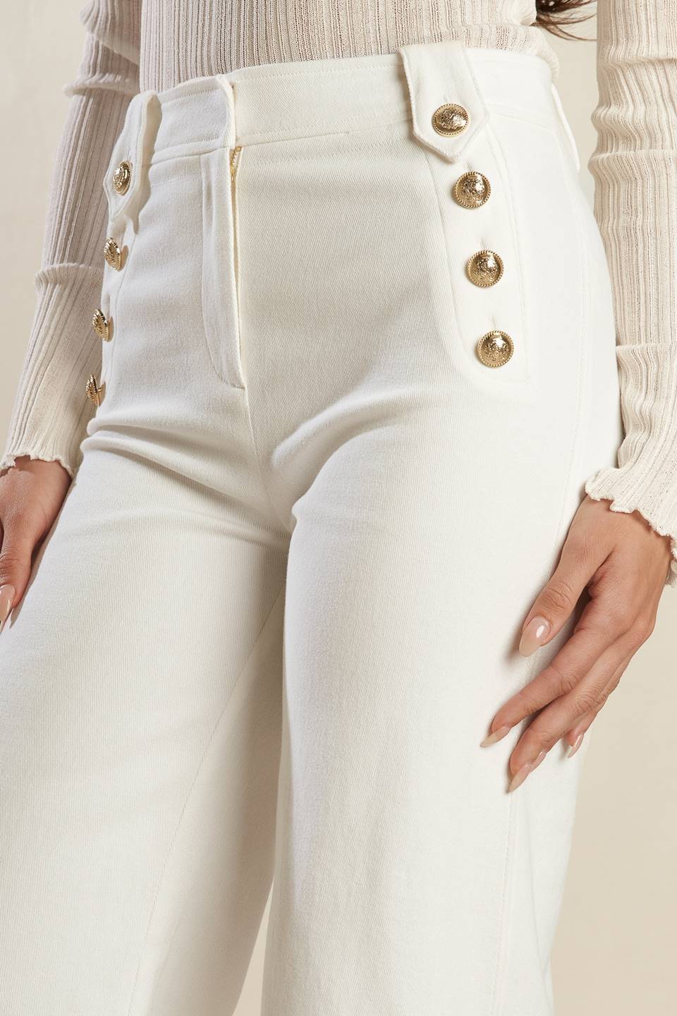 A solid woven white pant featuring front closure, button detail at pocket opening and wide leg.