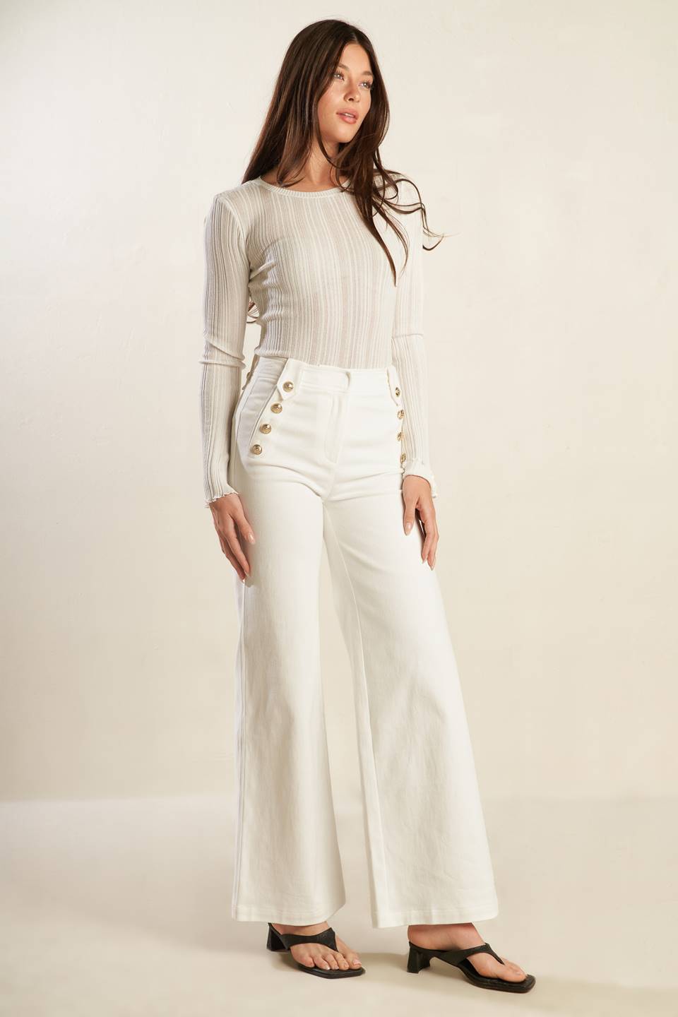 A solid woven white pant featuring front closure, button detail at pocket opening and wide leg.