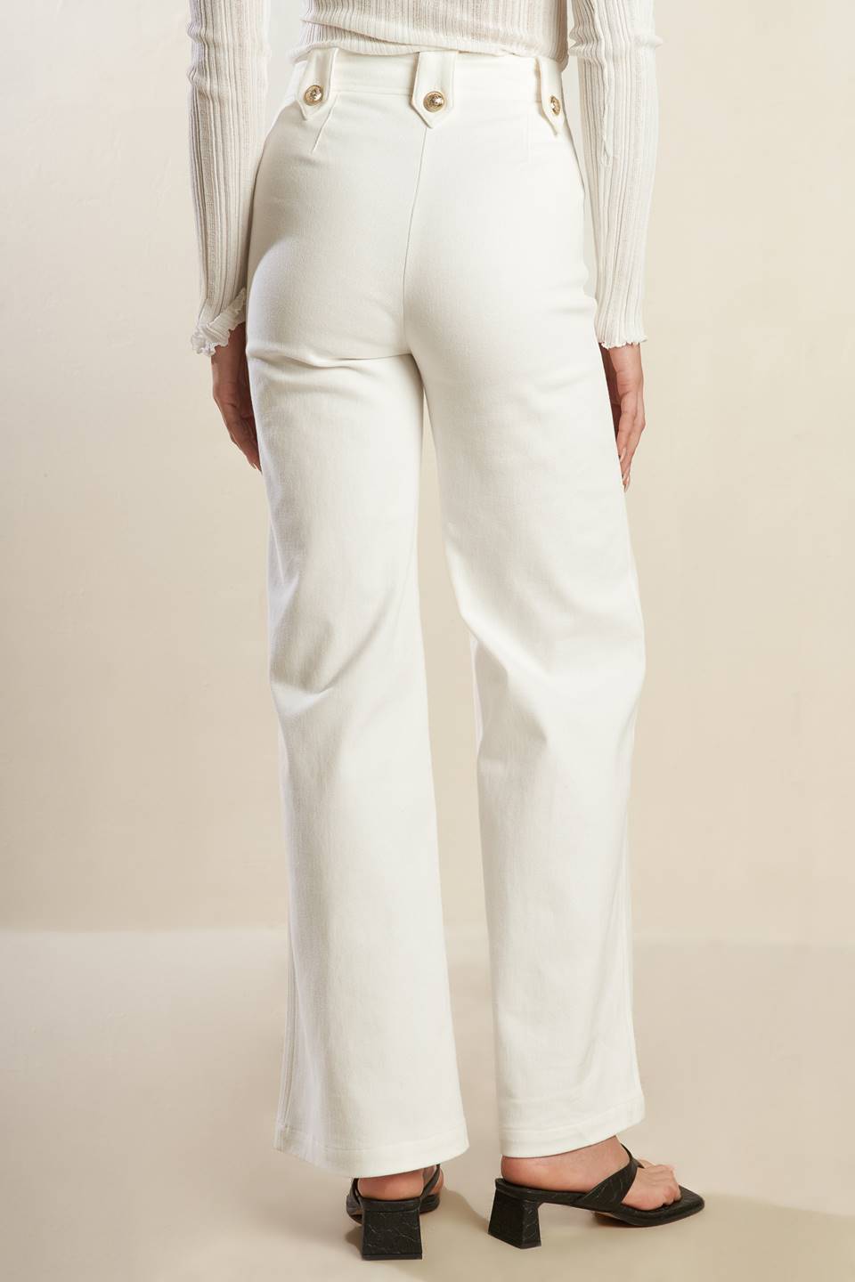 A solid woven white pant featuring front closure, button detail at pocket opening and wide leg.