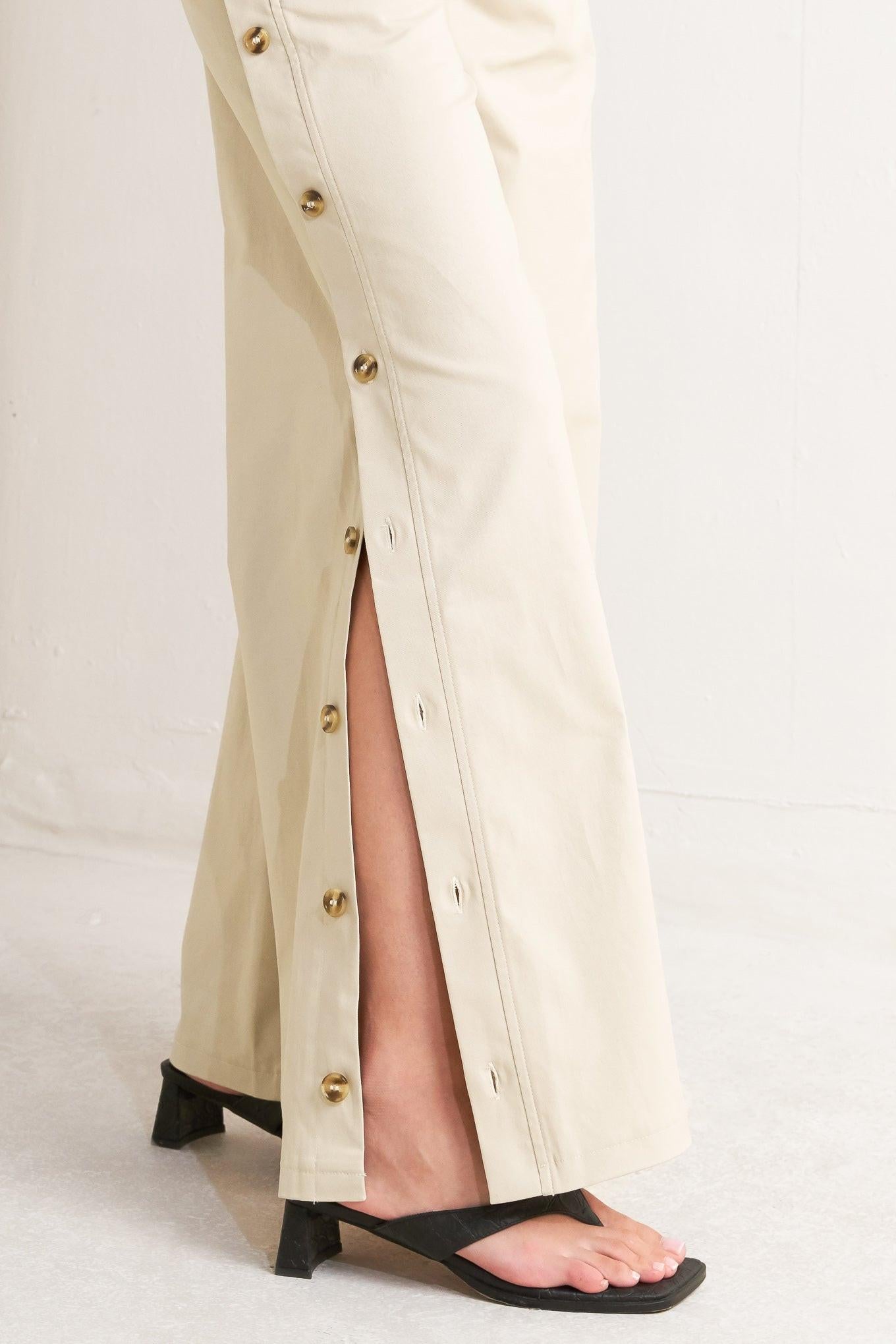 A solid woven pant featuring front closure, side button down, wide leg and skinny belt