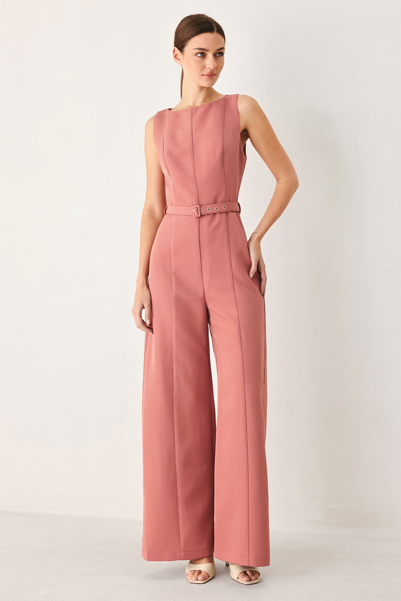 Woman wearing a pink jumpsuit on a white background