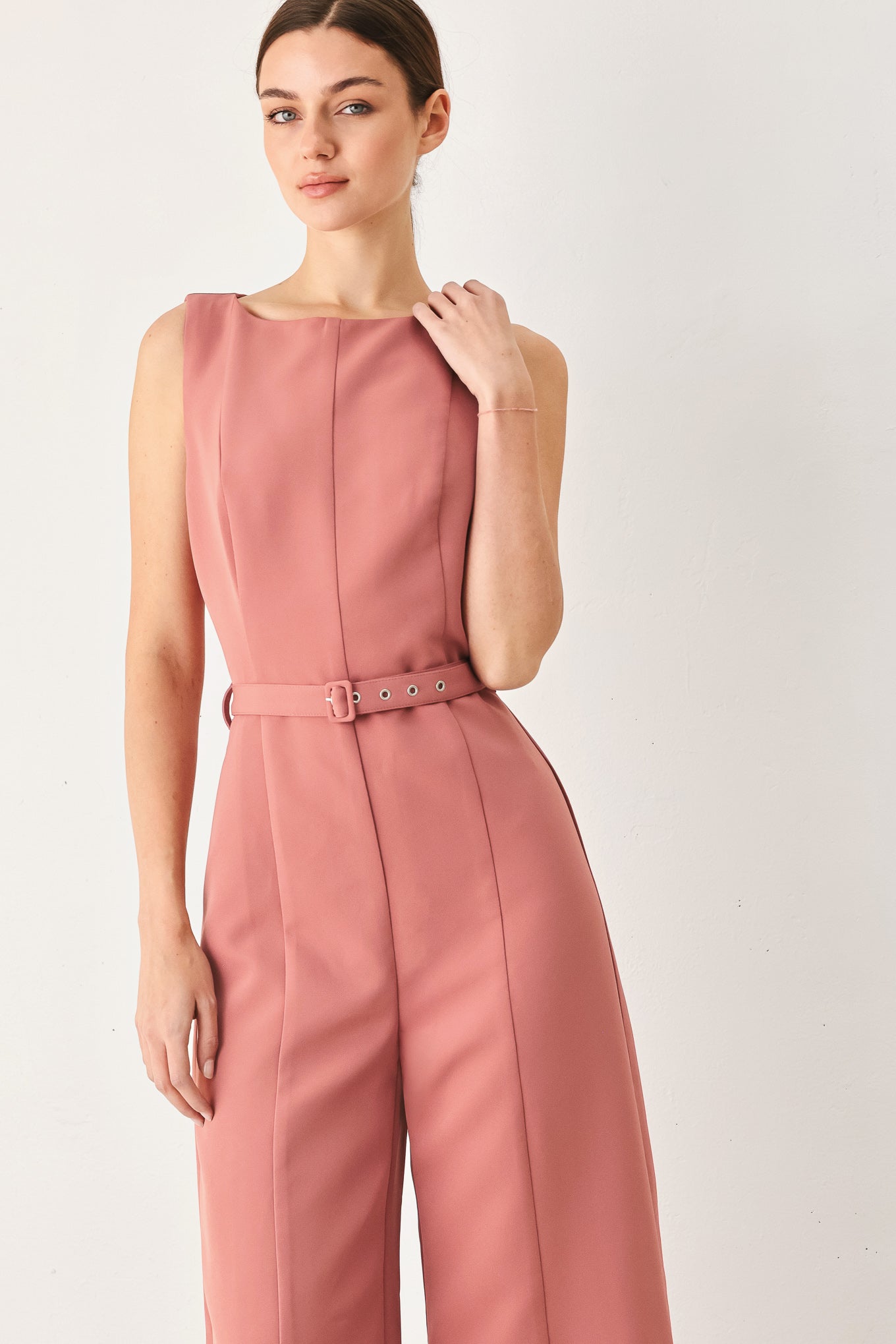 Woman wearing a sleeveless pink rose jumpsuit featuring wide neckline, self belt, wide leg and back zipper closure | FREEMARKET