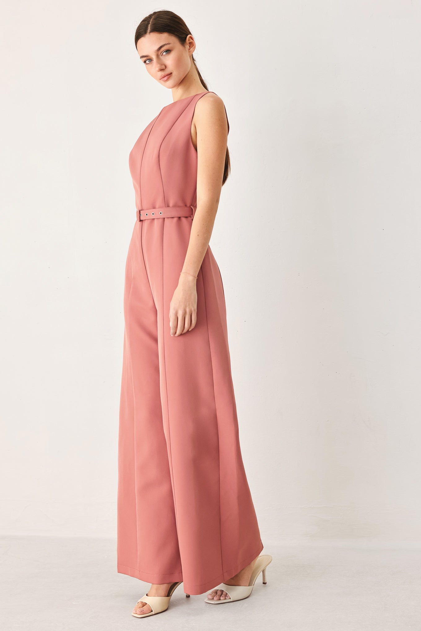 Woman wearing a sleeveless pink rose jumpsuit featuring wide neckline, self belt, wide leg and back zipper closure | FREEMARKET