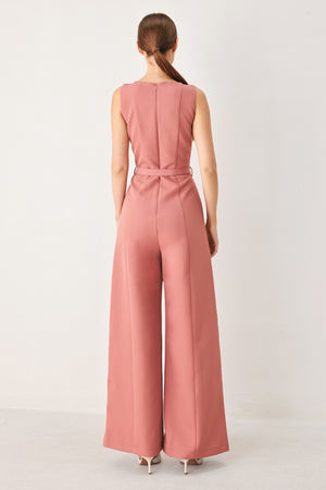 Woman wearing a sleeveless pink rose jumpsuit featuring wide neckline, self belt, wide leg and back zipper closure | FREEMARKET