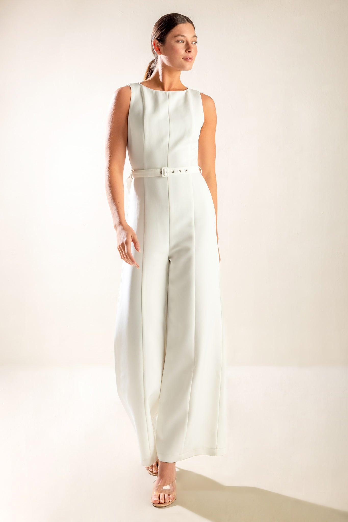 Woman wearing a sleeveless white jumpsuit featuring wide neckline, self belt, wide leg and back zipper closure | FREEMARKET