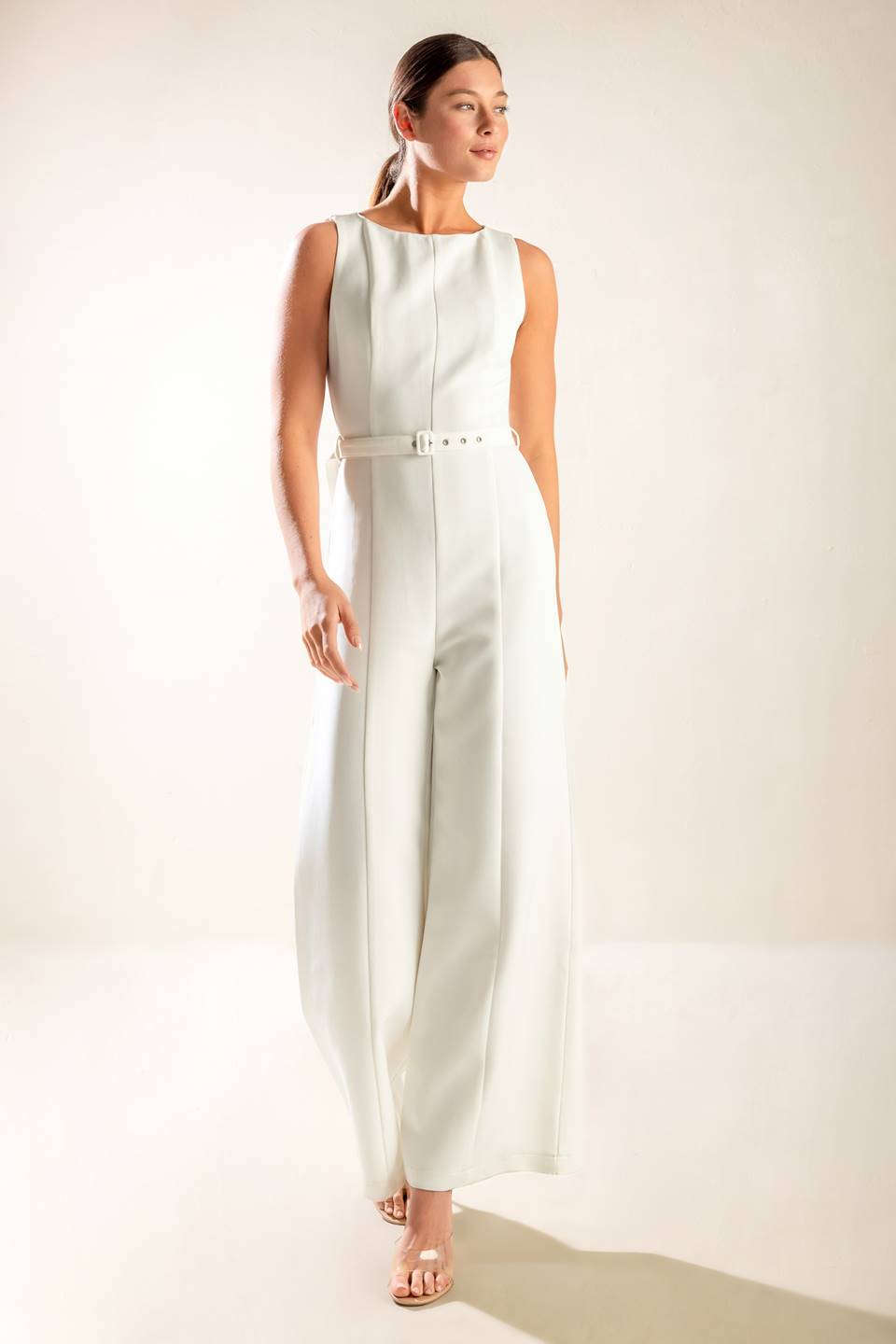 A solid woven jumpsuit featuring wide neckline, sleeveless, self belt, wide leg and back zipper closure.