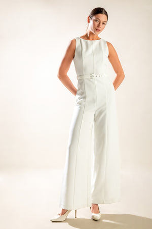 Woman wearing a white sleeveless jumpsuit against a plain background