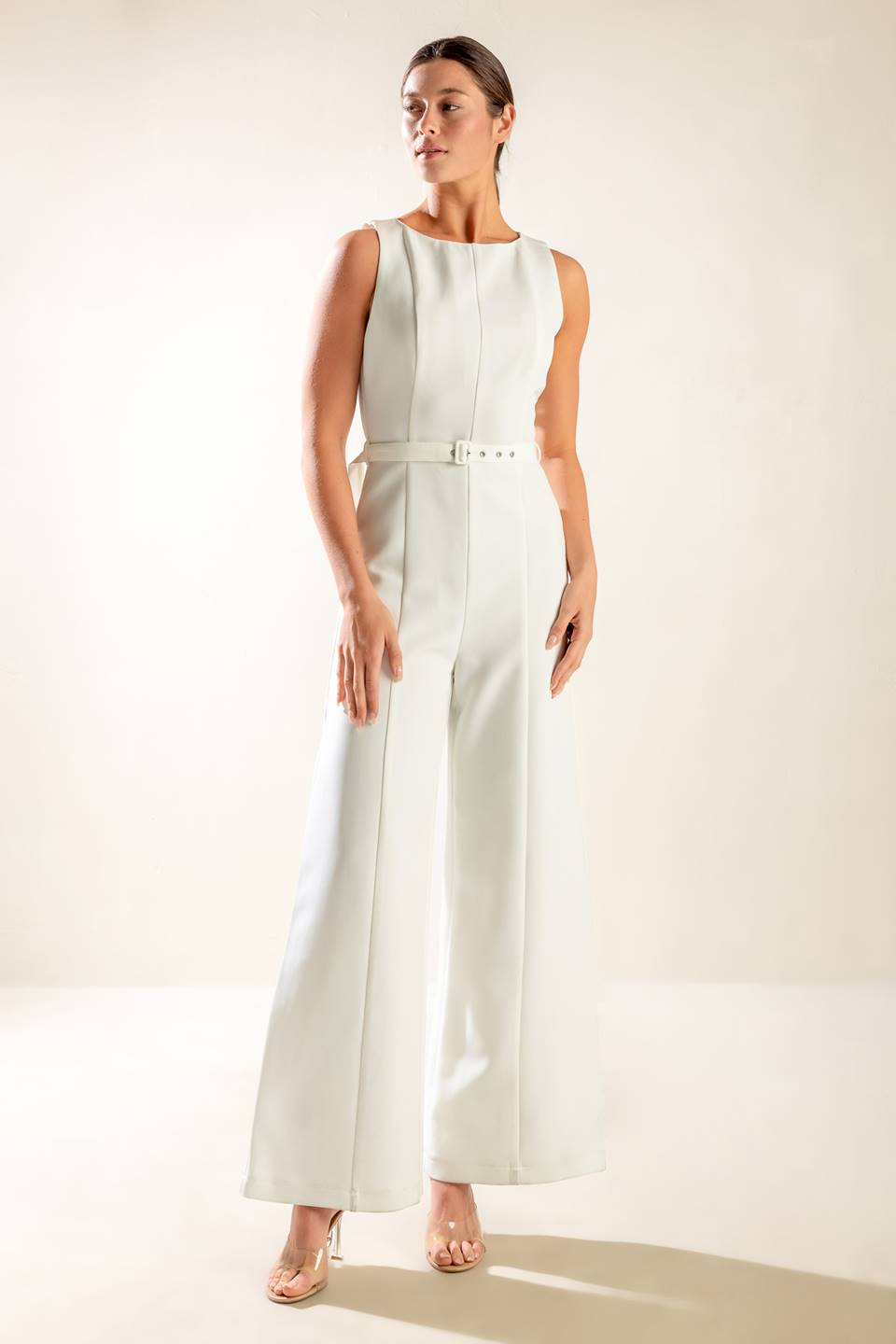 A solid woven jumpsuit featuring wide neckline, sleeveless, self belt, wide leg and back zipper closure.