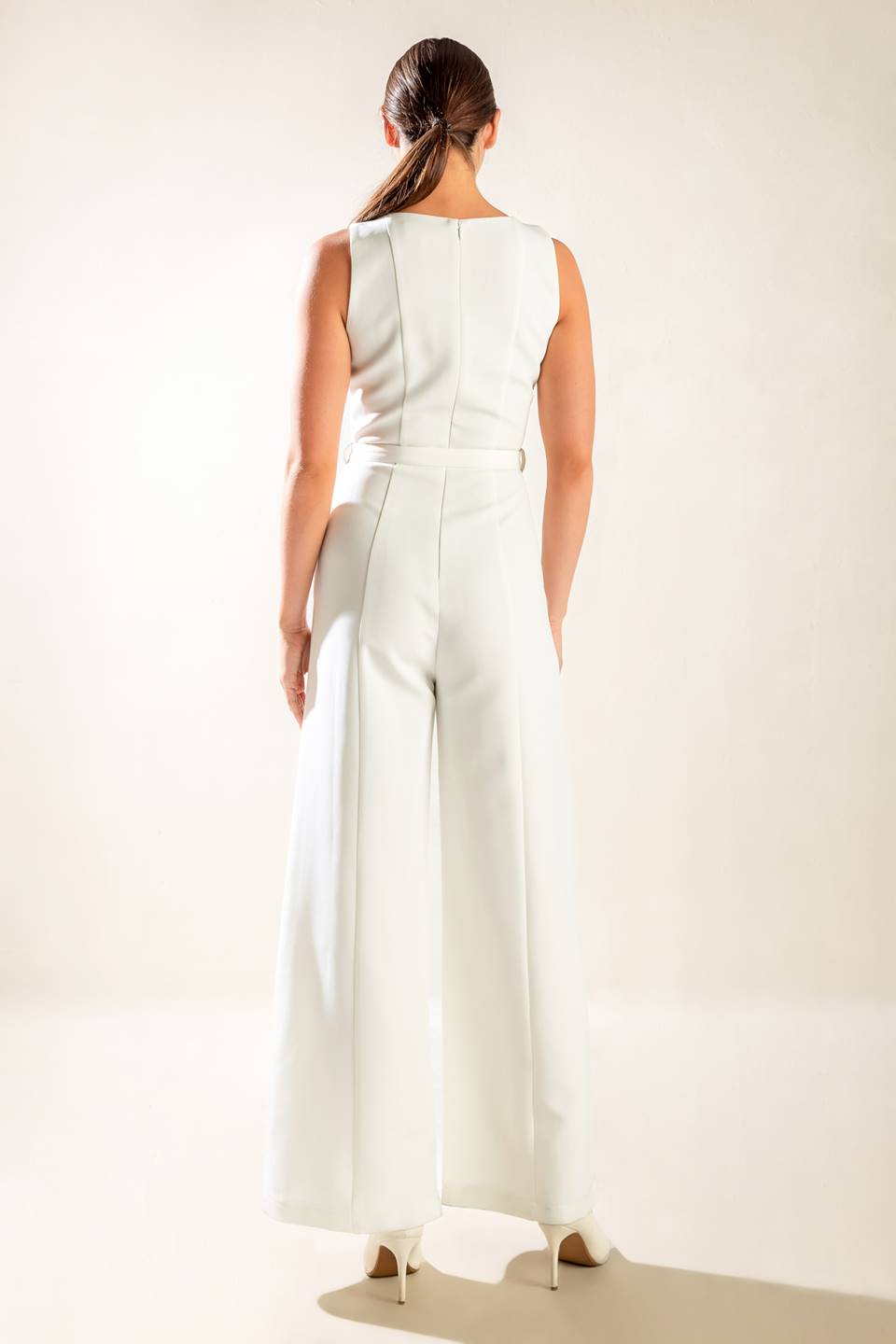 A solid woven jumpsuit featuring wide neckline, sleeveless, self belt, wide leg and back zipper closure.