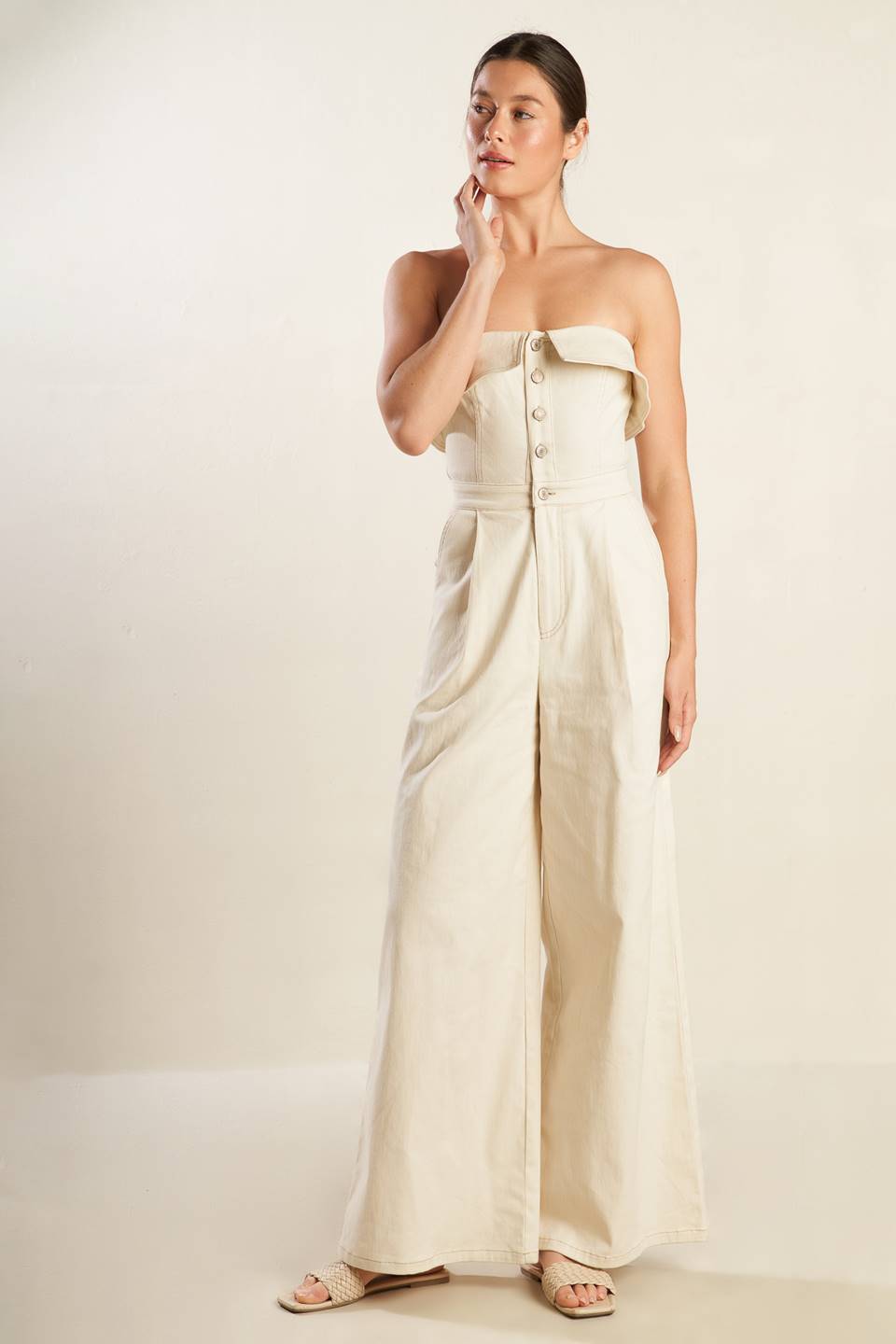 A strapless solid woven jumpsuit featuring front button down and zipper closure, side pockets and wide leg.