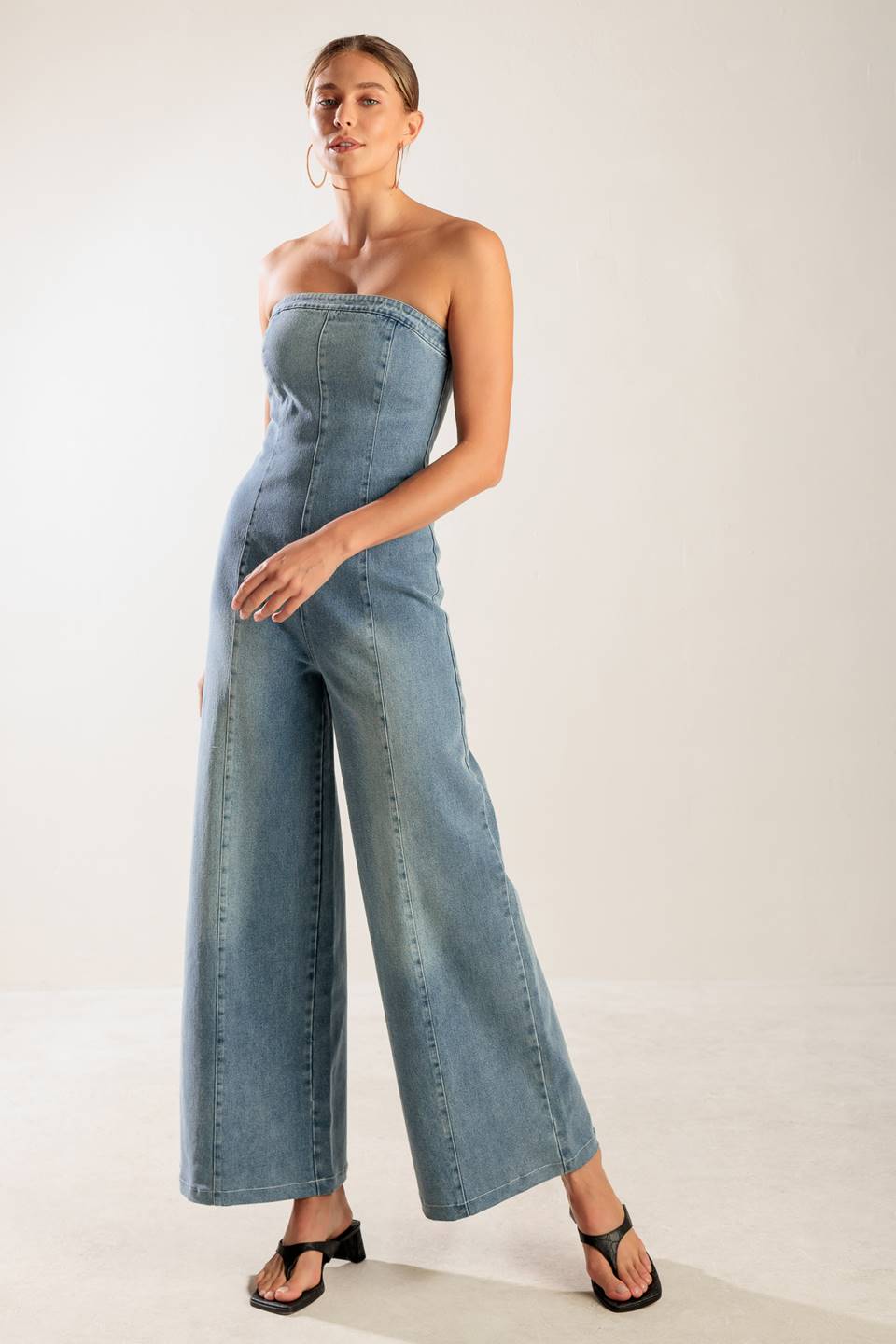 A washed denim jumpsuit featuring strapless, wide leg and back zipper closure