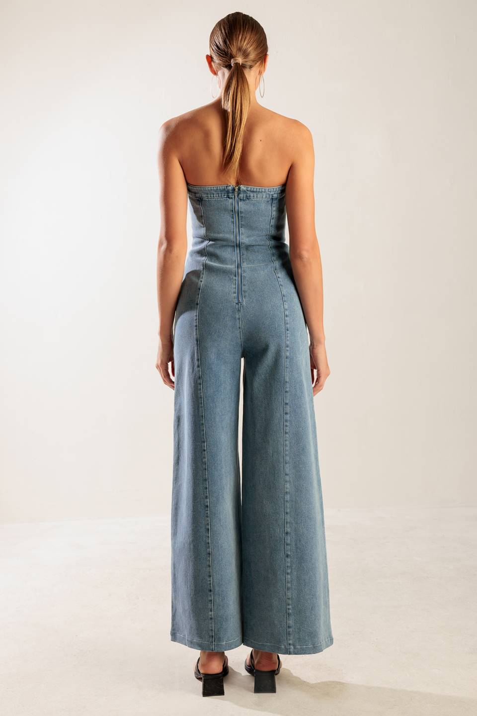 A washed denim jumpsuit featuring strapless, wide leg and back zipper closure