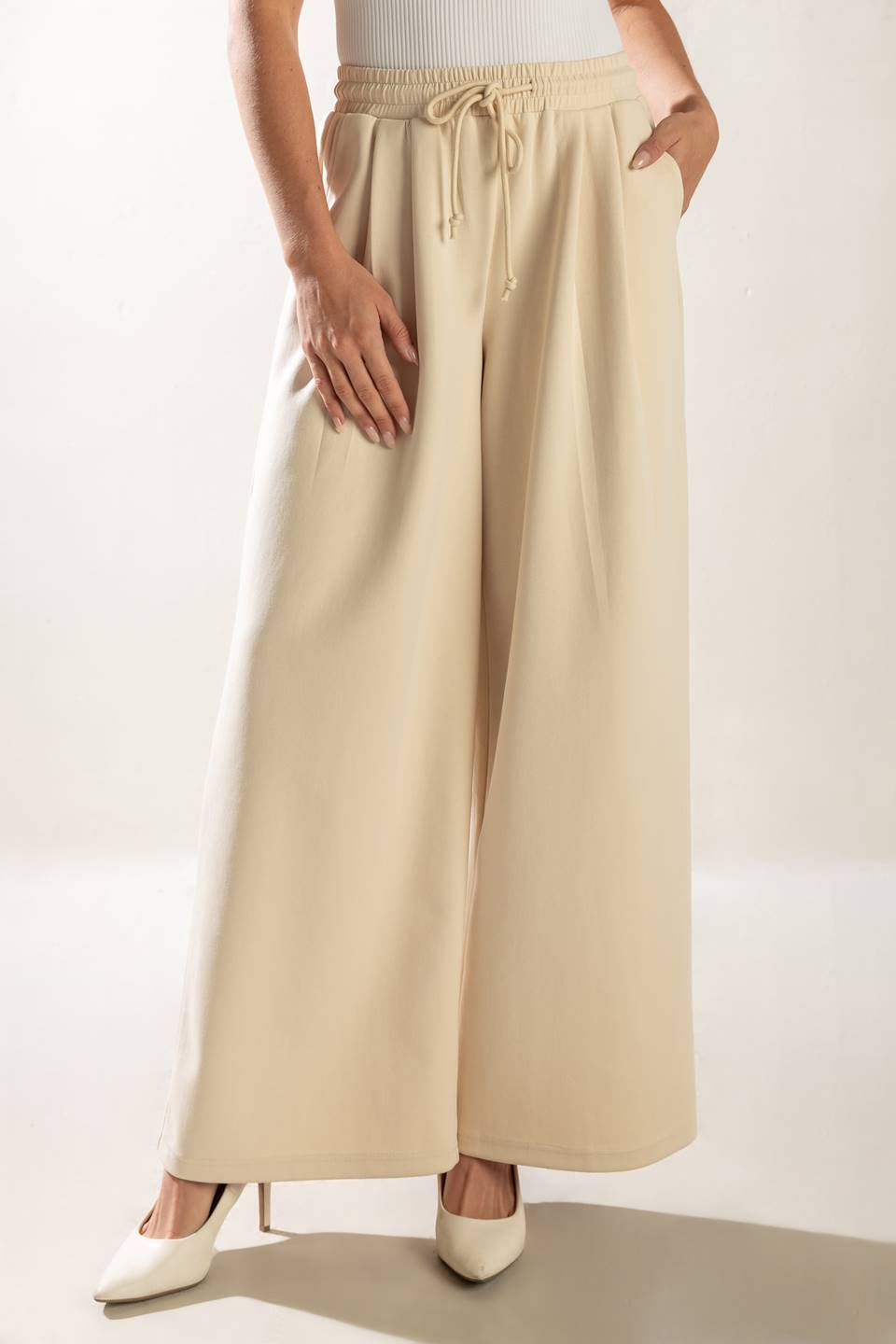 A solid wide-leg woven pant featuring elasticized waist with front tie and side pockets.