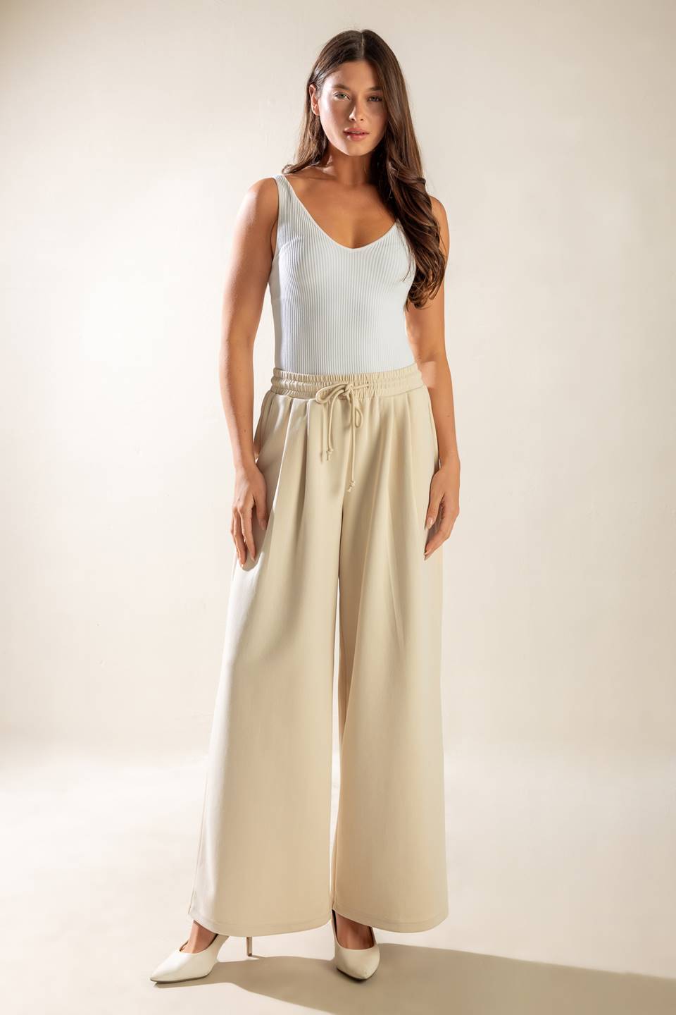 A solid wide-leg woven pant featuring elasticized waist with front tie and side pockets.