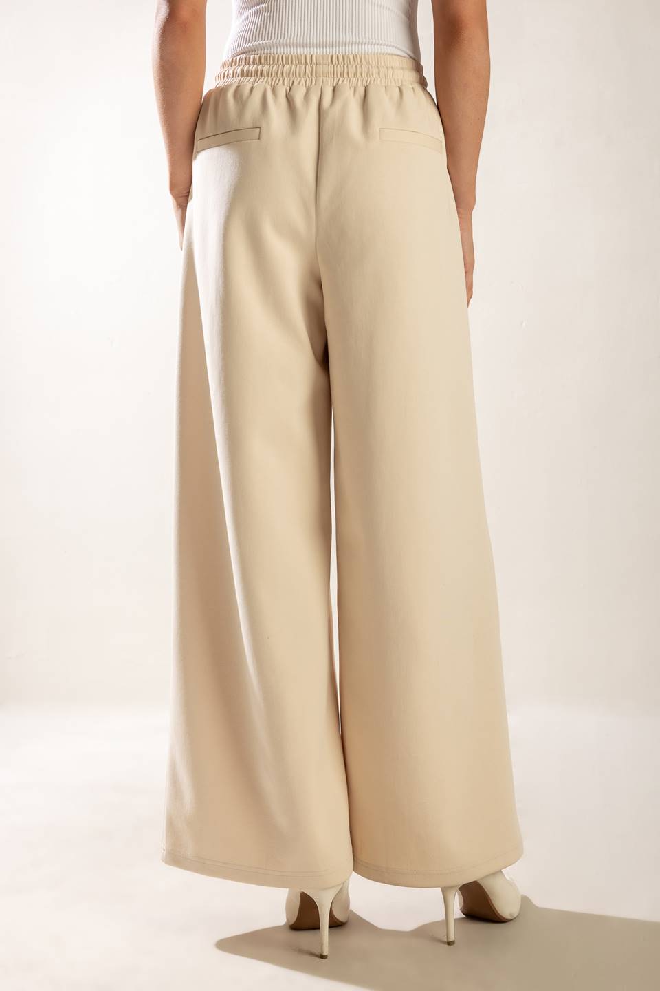 A solid wide-leg woven pant featuring elasticized waist with front tie and side pockets.