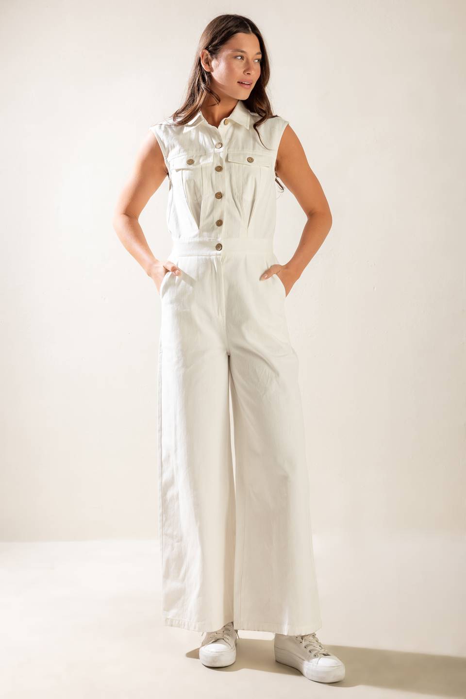 A sleeveless, solid wide-leg white woven jumpsuit featuring collar, button down and zipper closure, featuring side and back pockets.