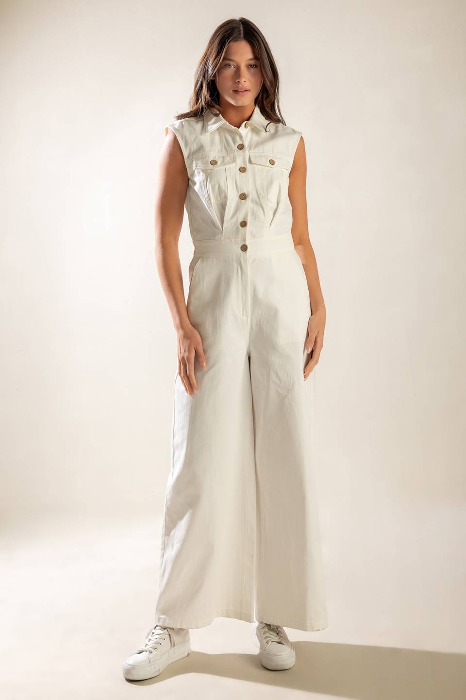 A sleeveless, solid wide-leg white woven jumpsuit featuring collar, button down and zipper closure, featuring side and back pockets.