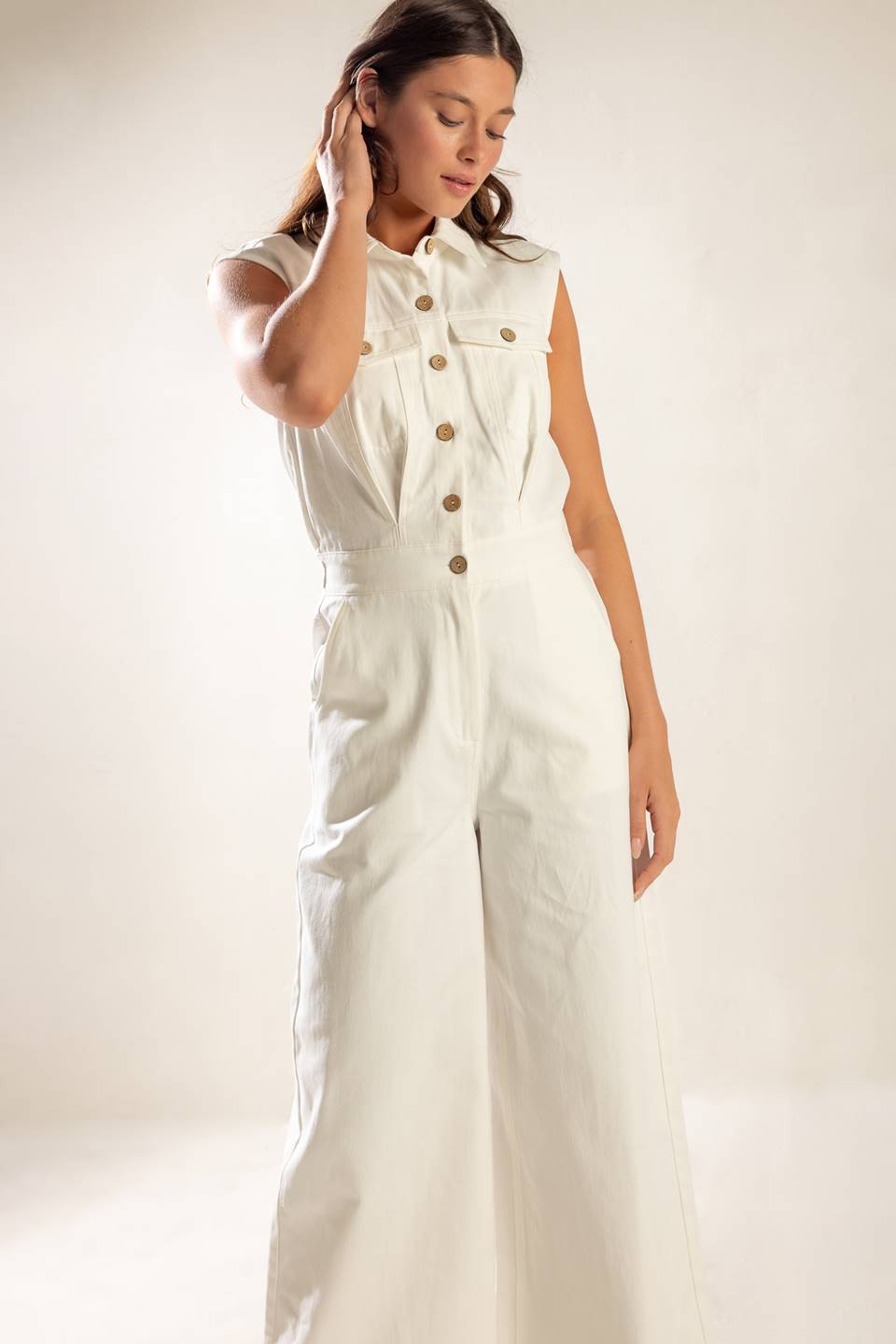 A sleeveless, solid wide-leg white woven jumpsuit featuring collar, button down and zipper closure, featuring side and back pockets.