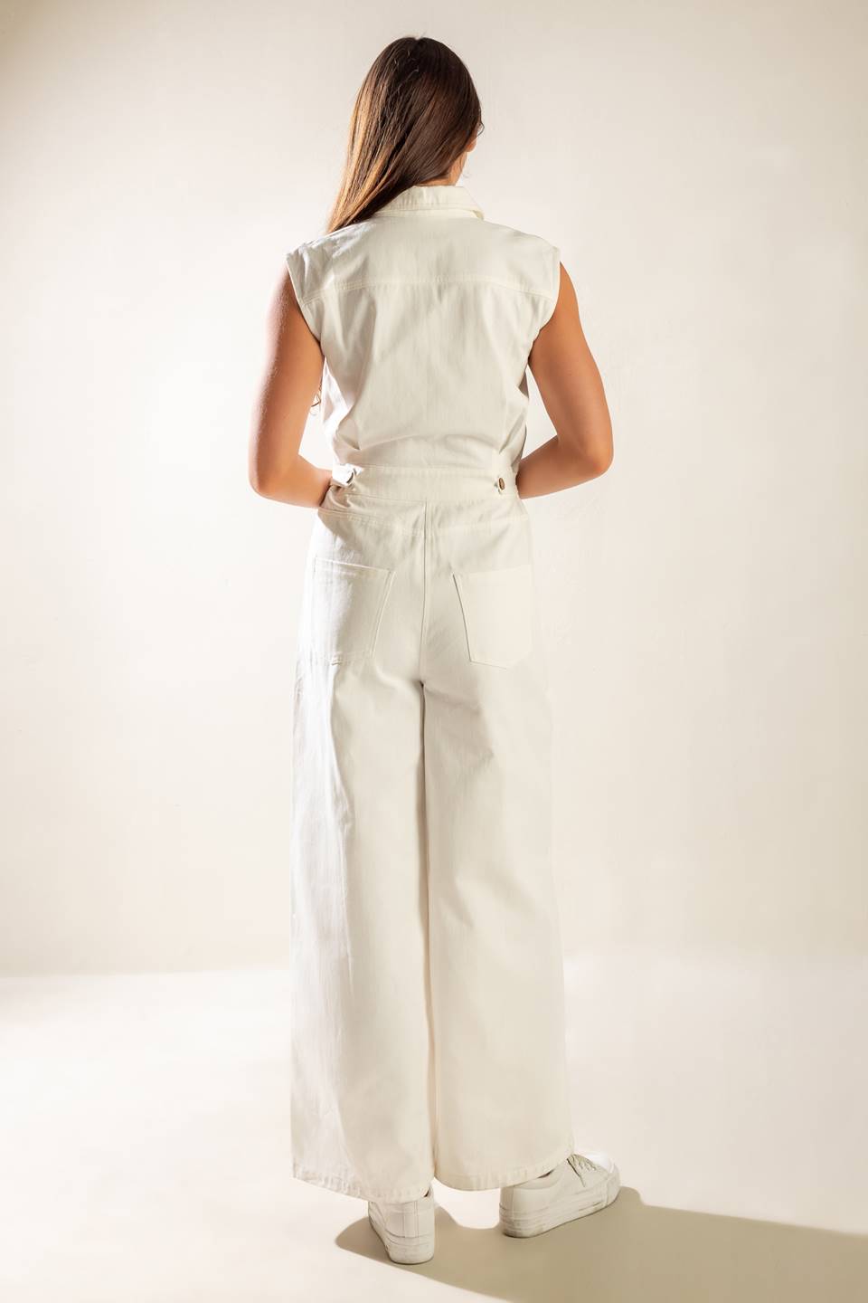 A sleeveless, solid wide-leg white woven jumpsuit featuring collar, button down and zipper closure, featuring side and back pockets.