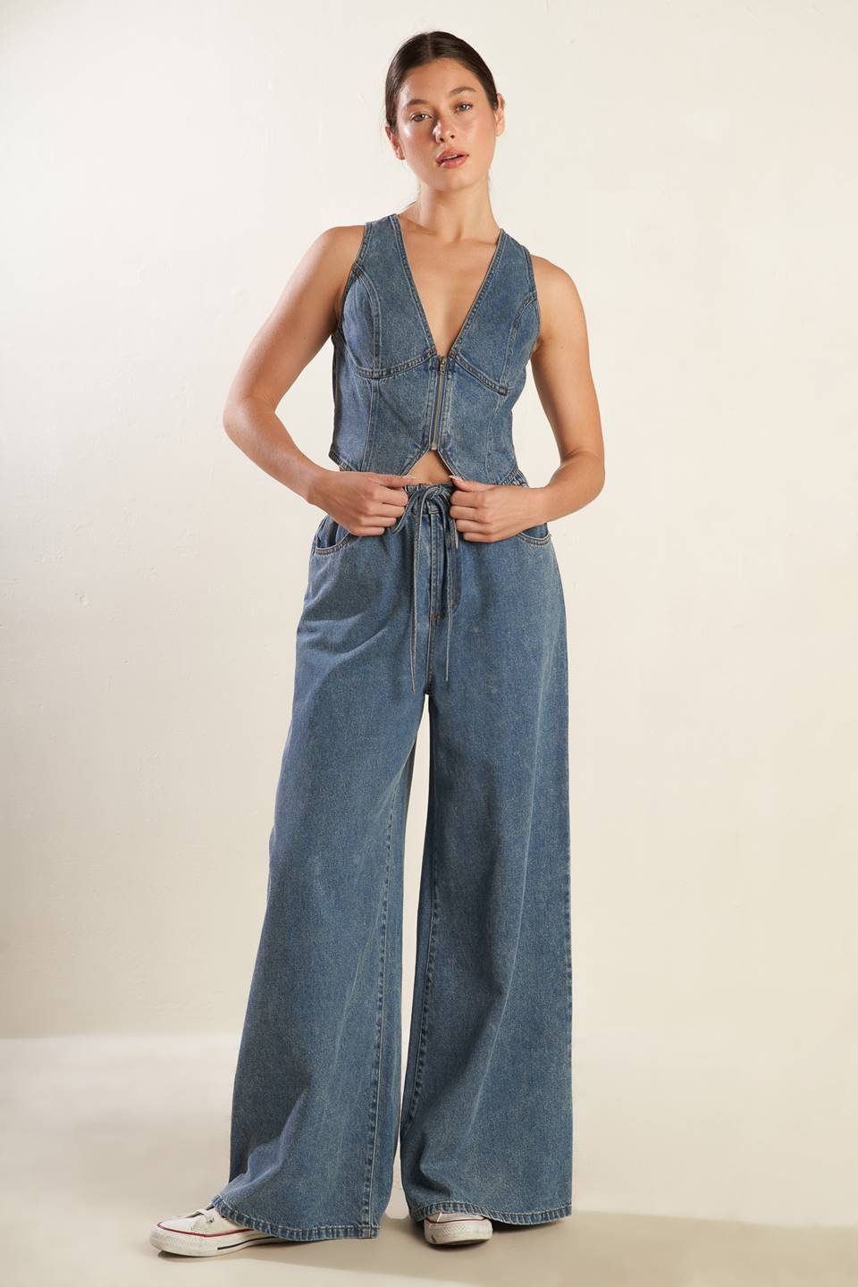 A washed denim pant featuring elasticized waistband with front tie, side pockets and wide leg.