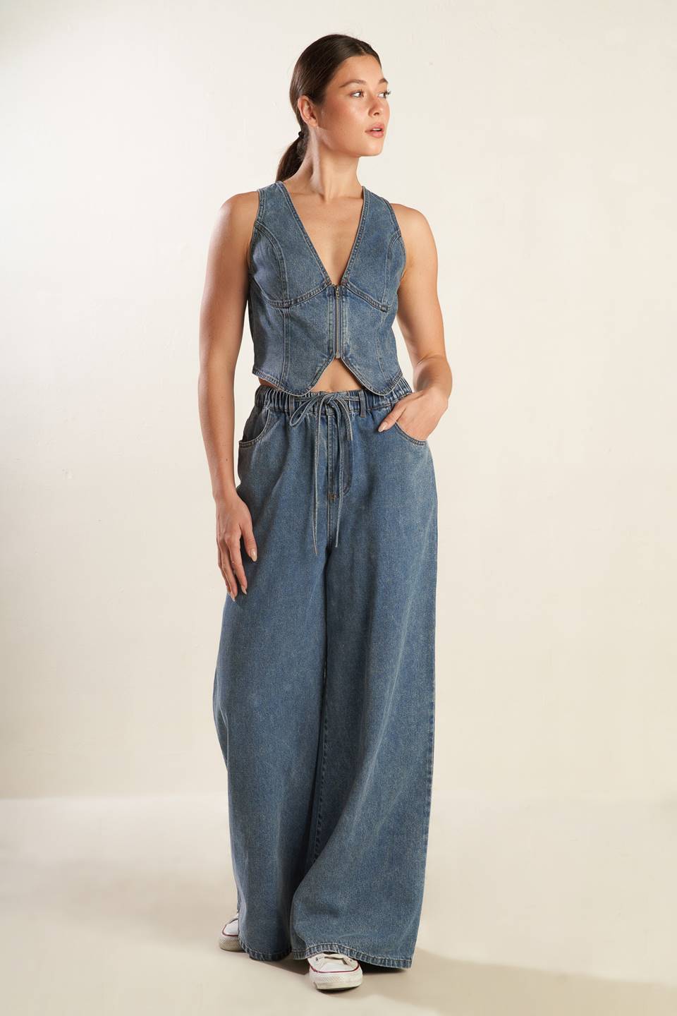 A washed denim pant featuring elasticized waistband with front tie, side pockets and wide leg.