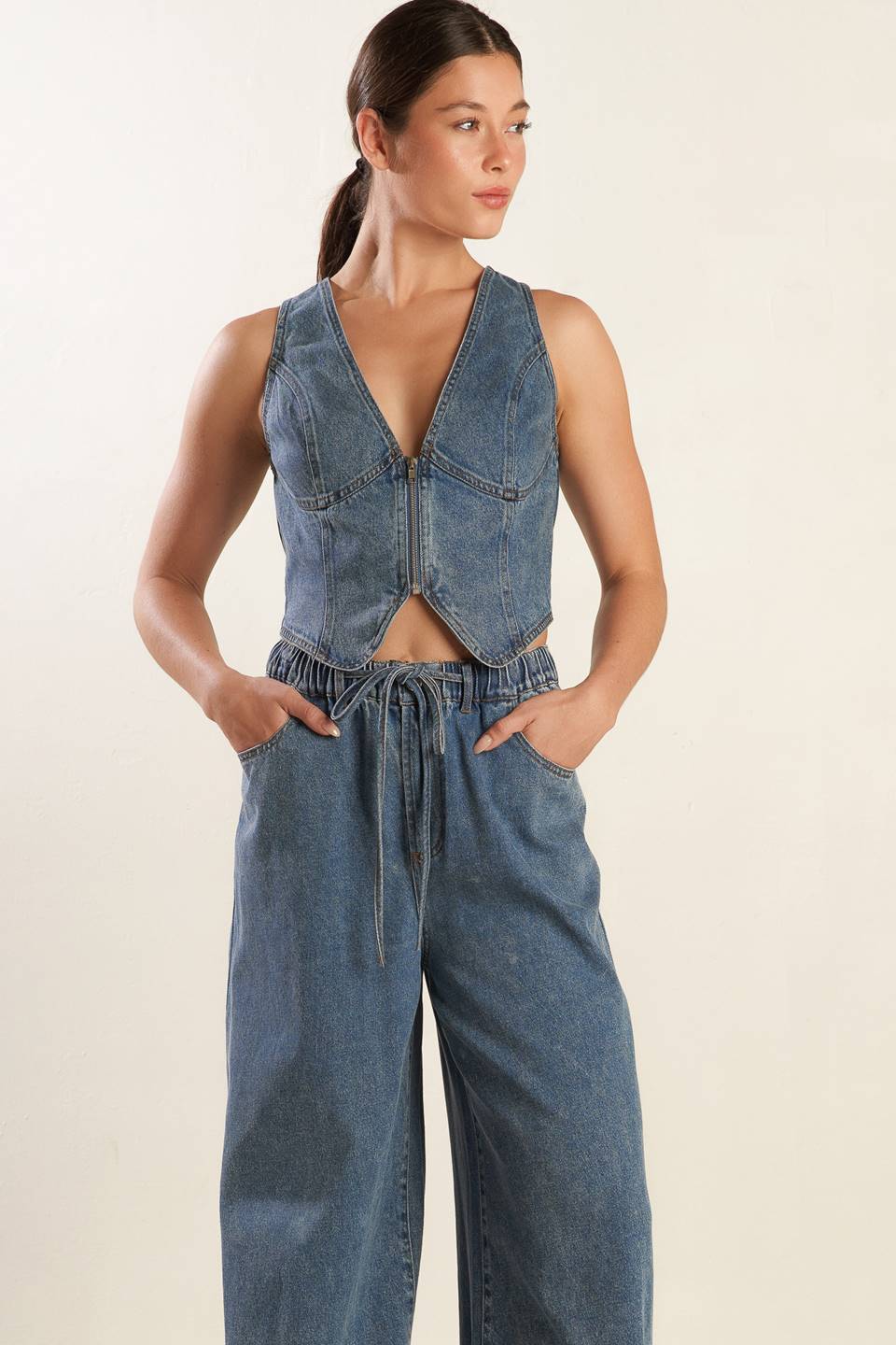 A washed denim pant featuring elasticized waistband with front tie, side pockets and wide leg.