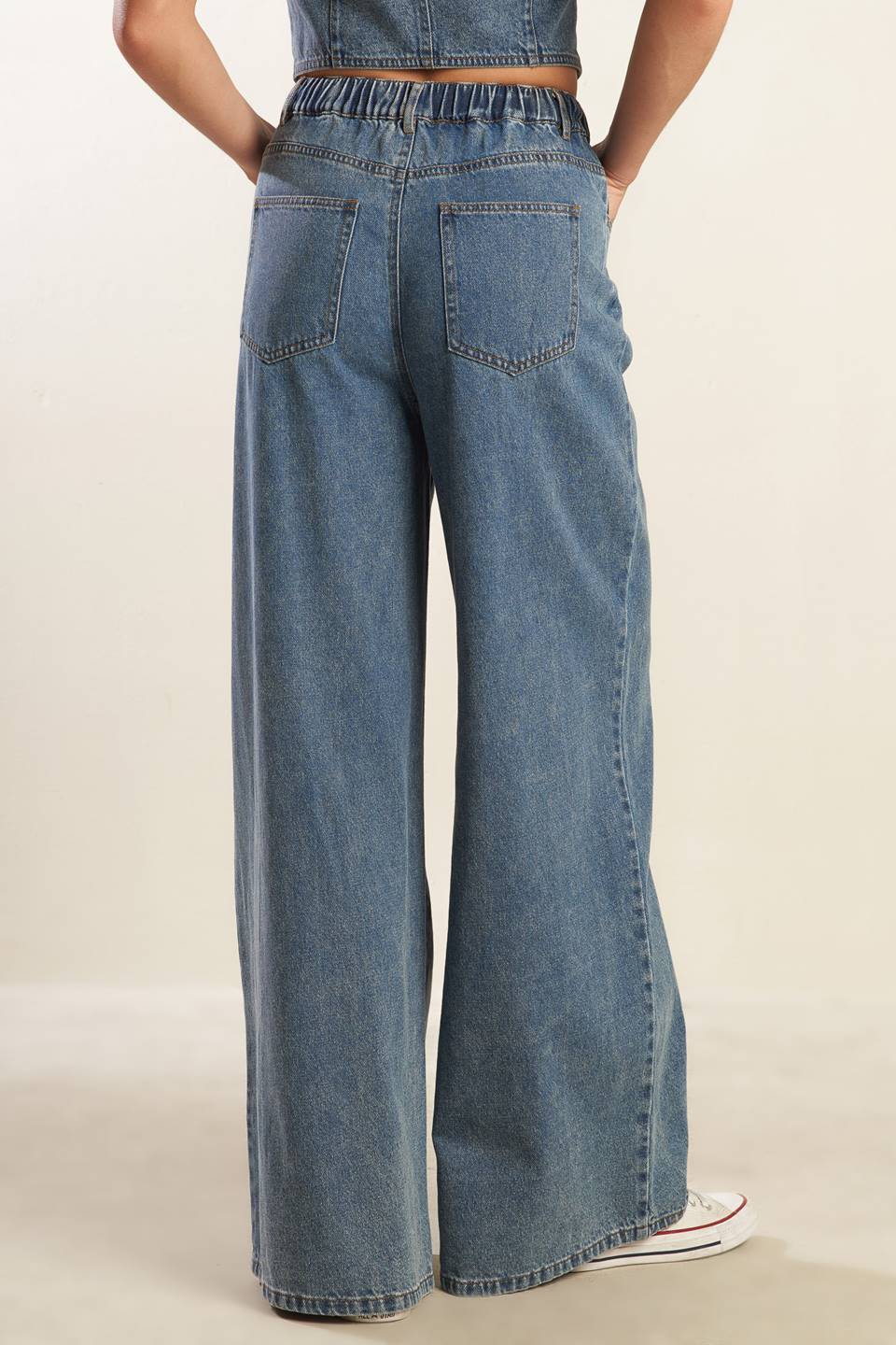 A washed denim pant featuring elasticized waistband with front tie, side pockets and wide leg.