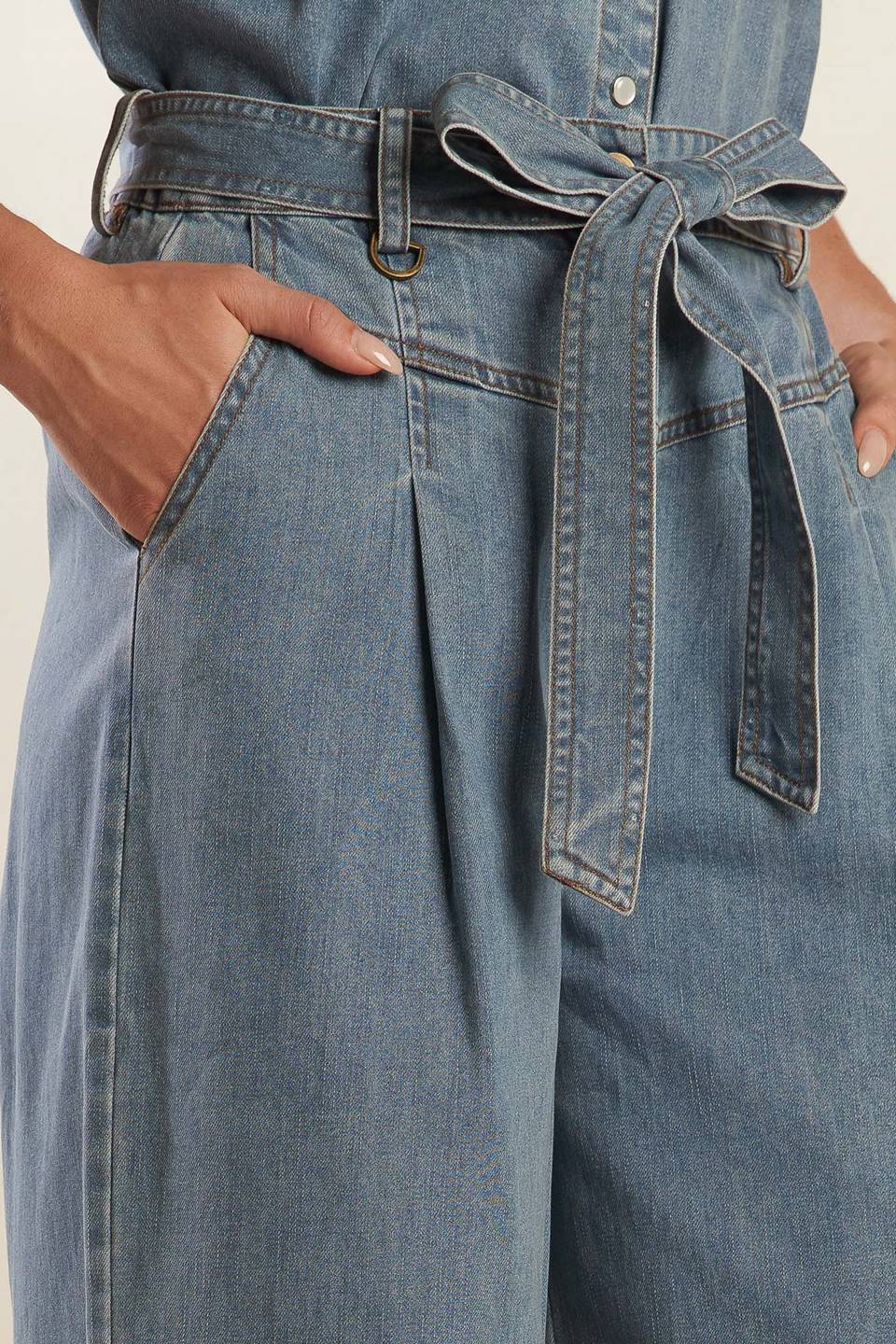 A washed light denim pant featuring front closure with self belt, side pockets, wide leg and elasticized back waistband.