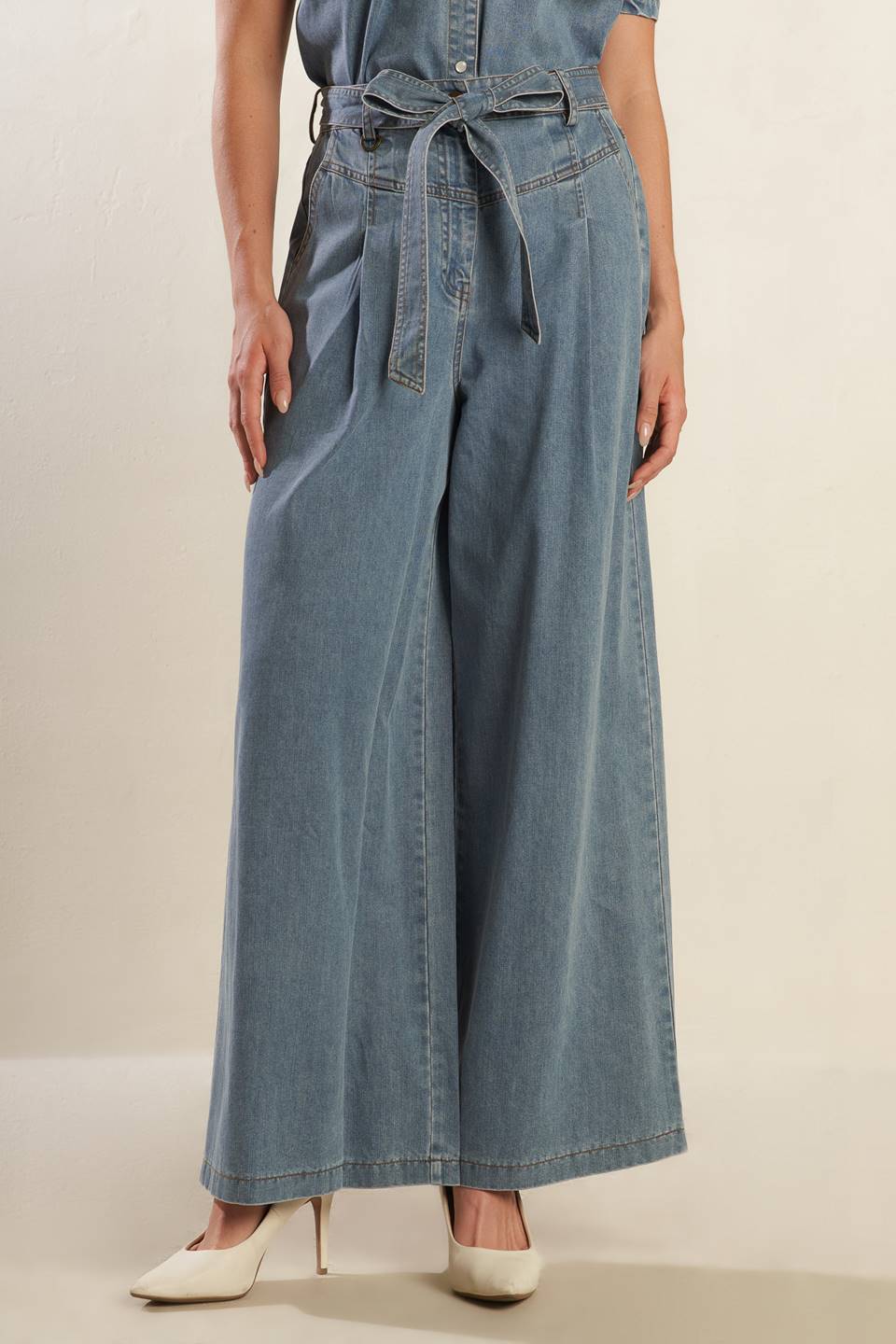 A washed light denim pant featuring front closure with self belt, side pockets, wide leg and elasticized back waistband.