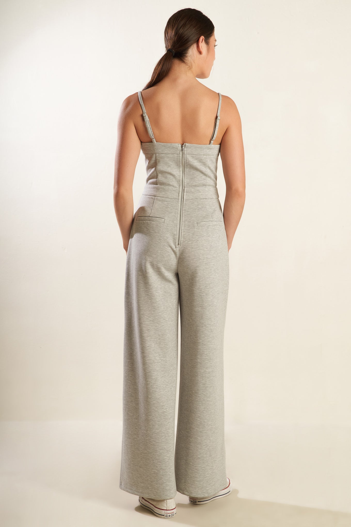 A solid heather grey knit jumpsuit featuring straight neckline with straps, button front detail, side pockets, wide leg and back zipper closure