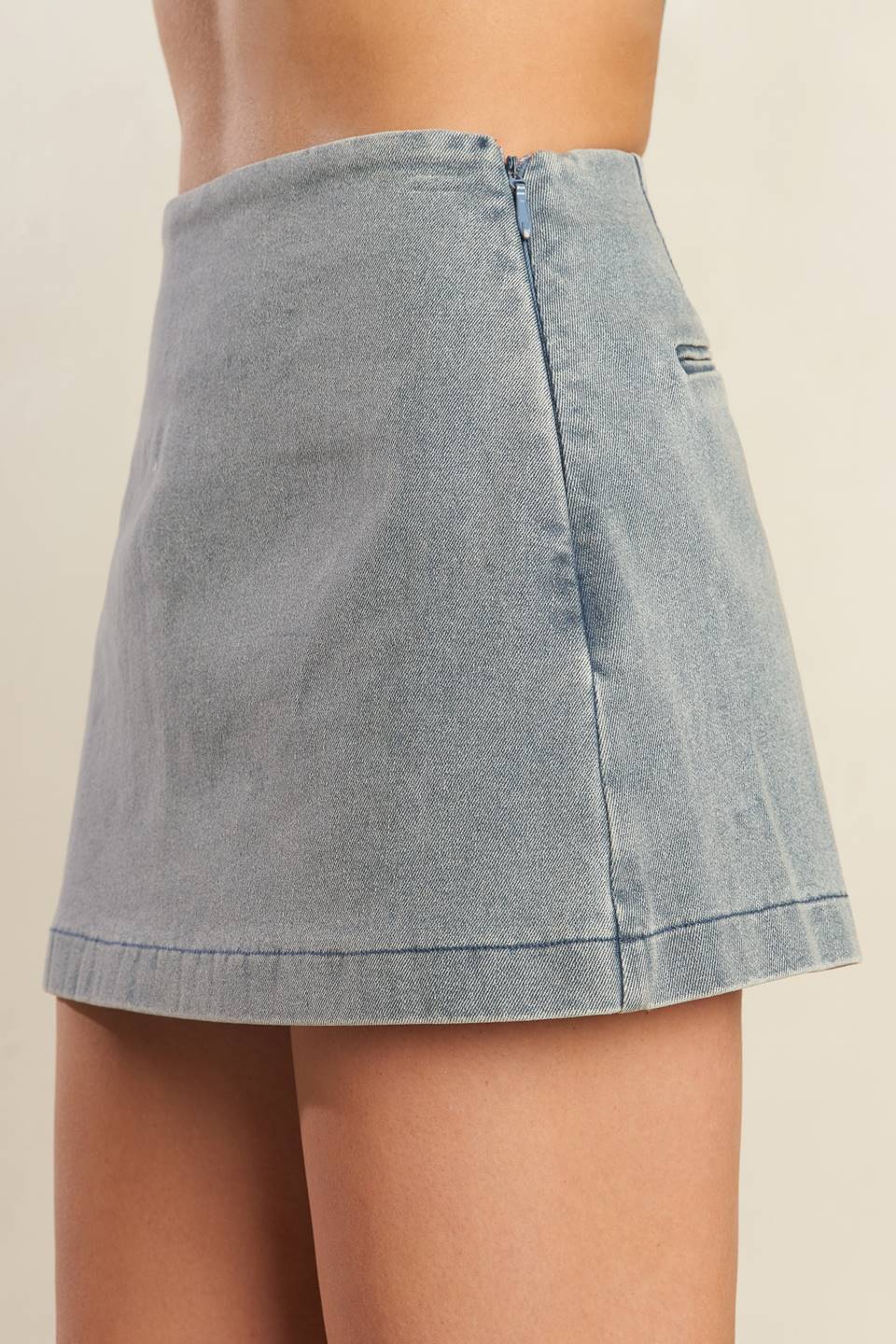 A solid denim mini skort with side zipper closure and back pockets.