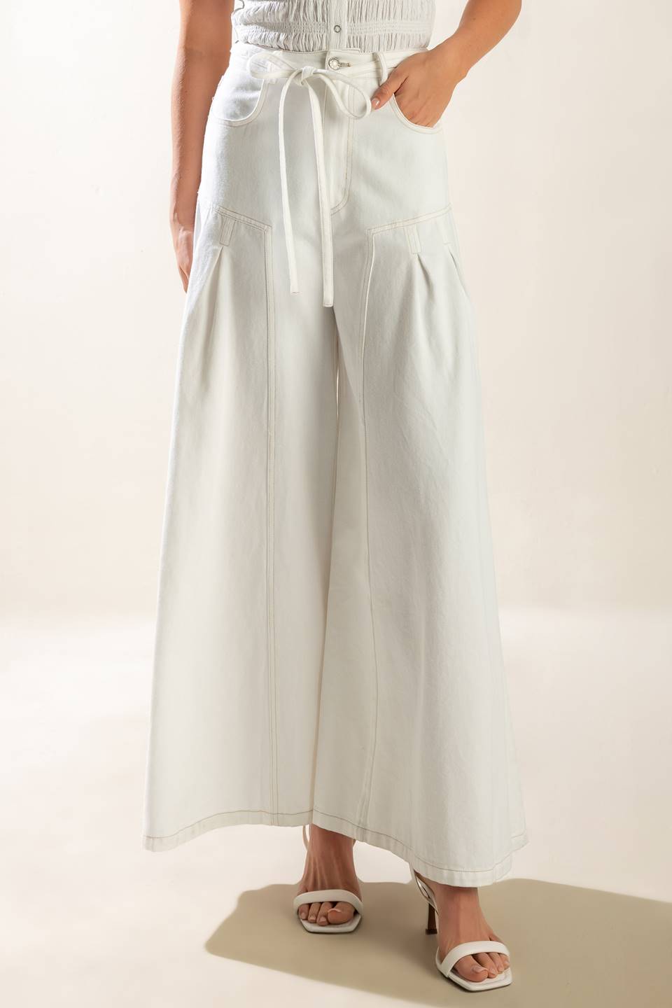 These white woven pants include a front closure, pockets, self-tie skinny belt, side pleats, and an extra wide leg for added comfort.