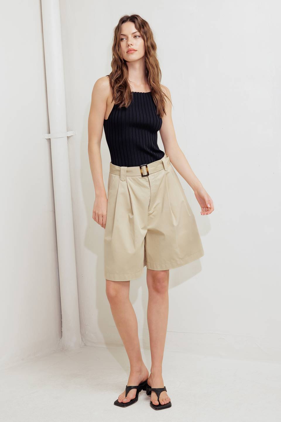 A solid woven bermuda short featuring front closure and self belt.