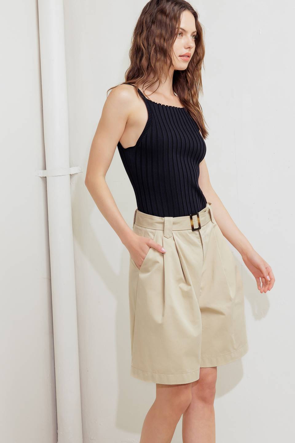 A solid woven bermuda short featuring front closure and self belt.