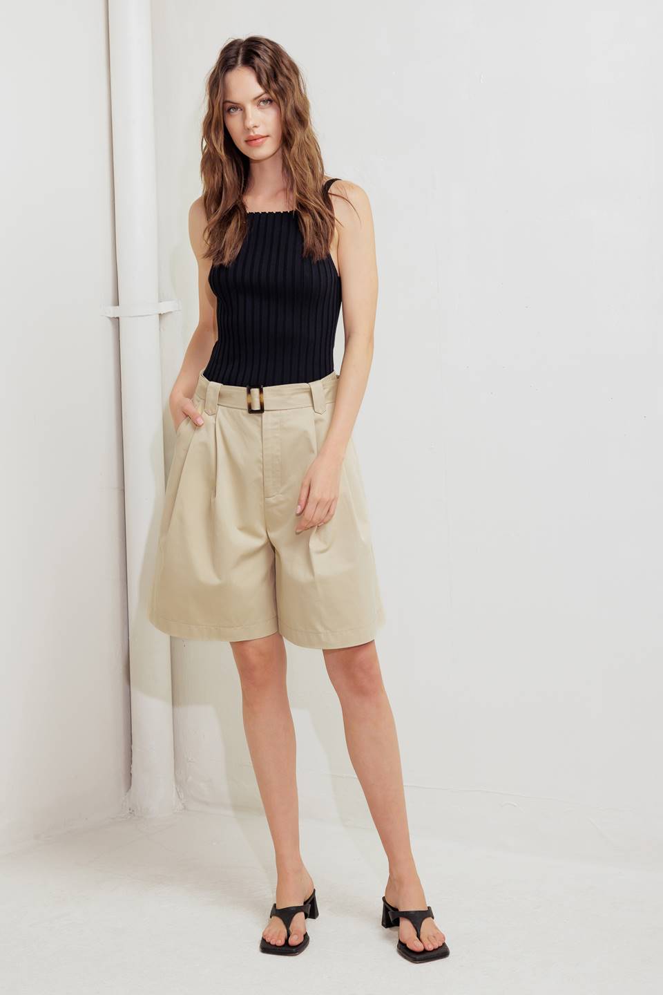 A solid woven bermuda short featuring front closure and self belt.