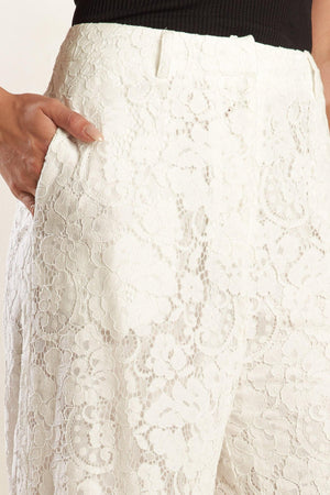A white woven lace pant featuring side pockets, belt loops, front closure and wide leg.