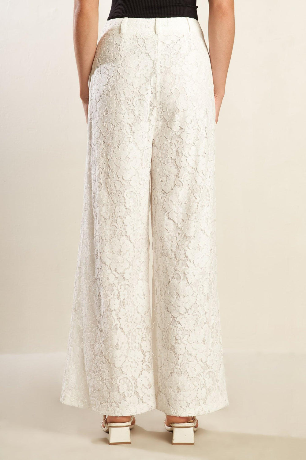 A white woven lace pant featuring side pockets, belt loops, front closure and wide leg.