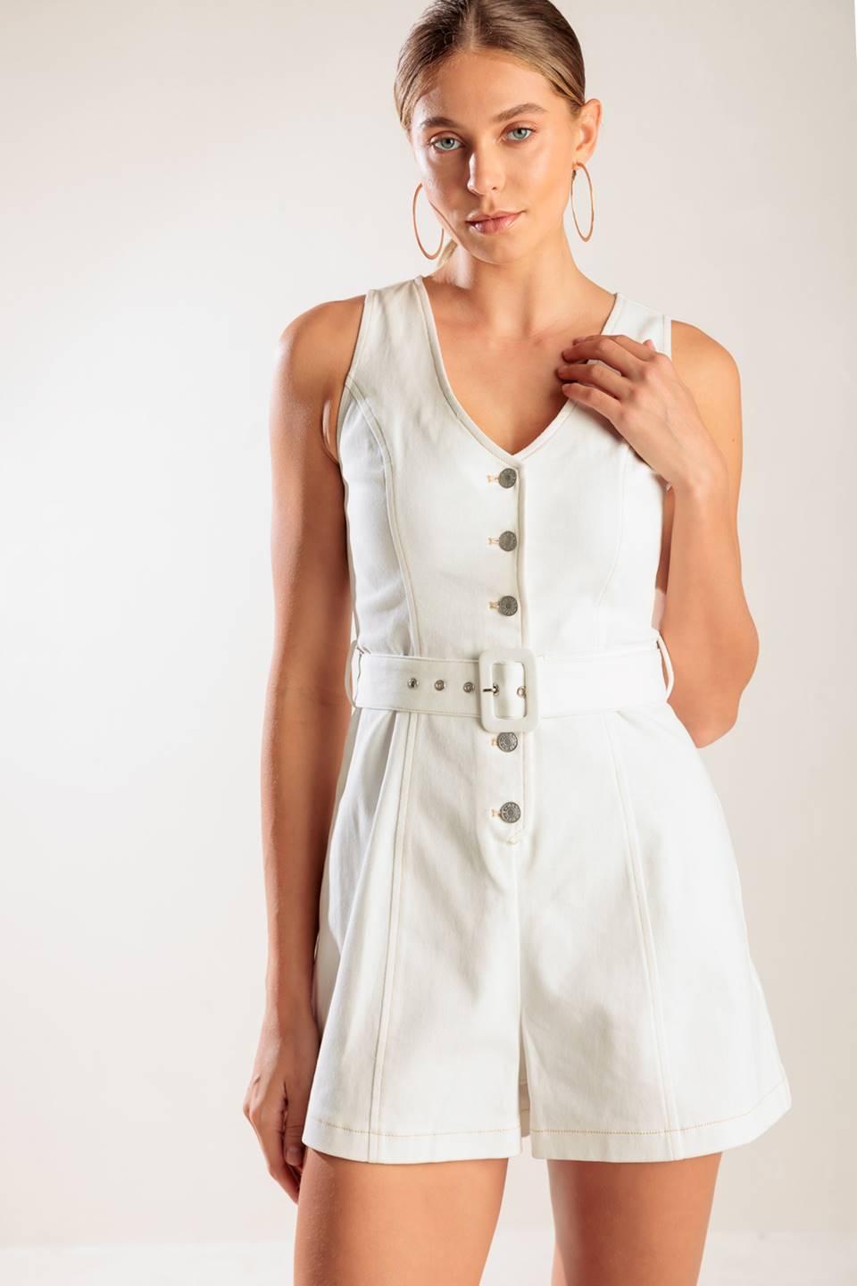 A solid white woven romper featuring V neckline, sleeveless, button down closure and self belt