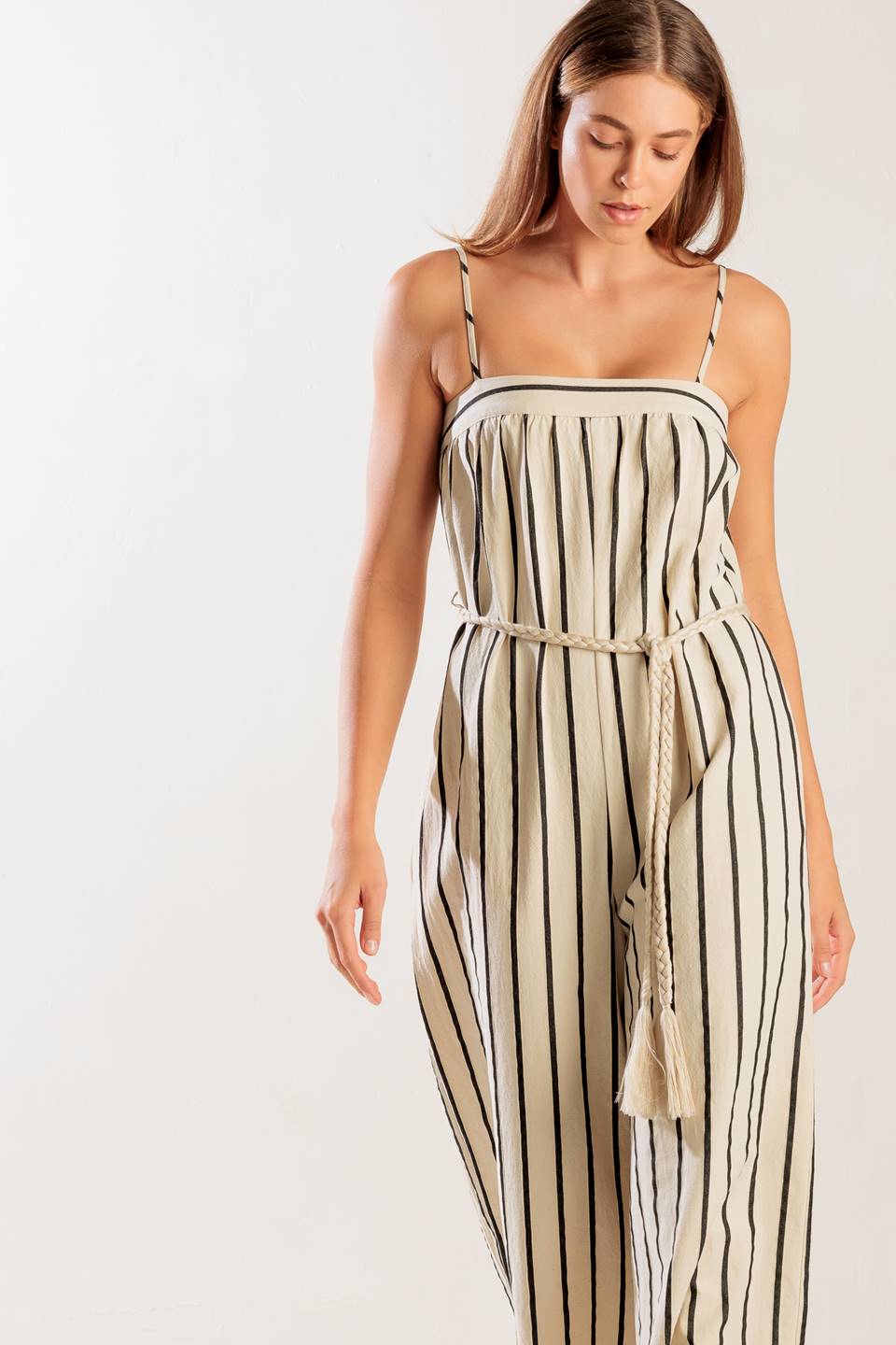 A striped woven jumpsuit featuring straight neckline, straps, side pockets, back closure and braided belt