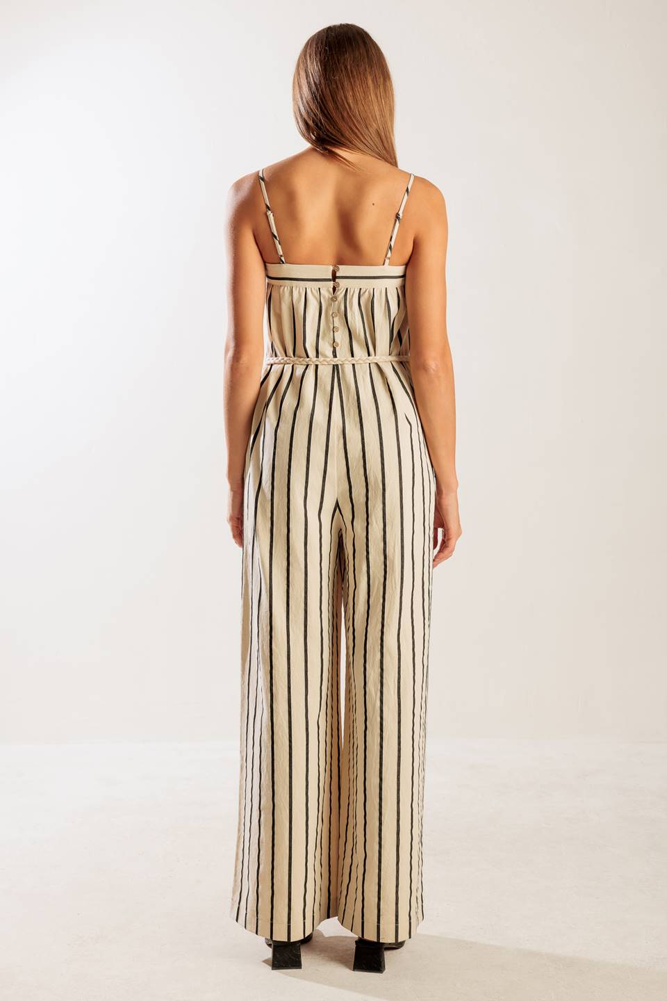 A striped woven jumpsuit featuring straight neckline, straps, side pockets, back closure and braided belt