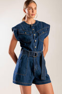 A denim romper featuring a round neckline, button down, cuffed sleeve, self belt, and pockets.